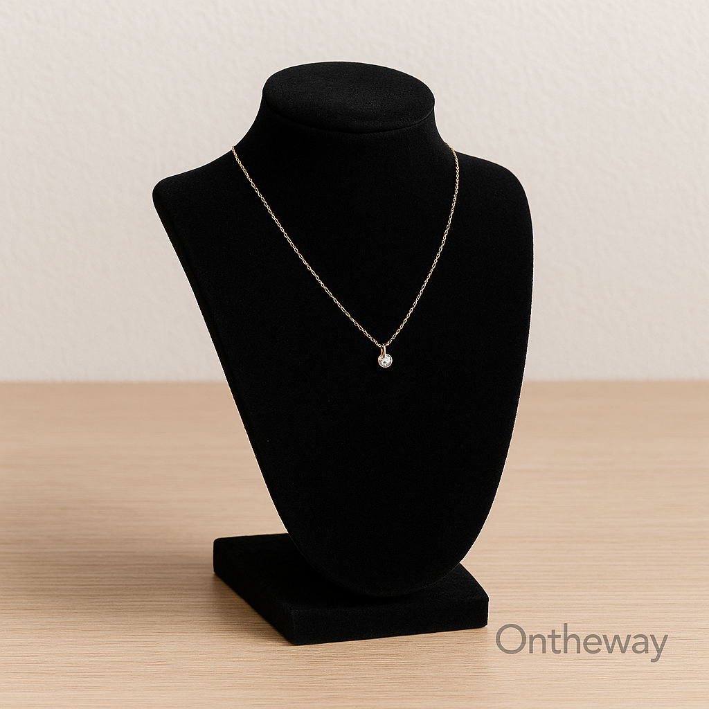A close-up photograph of a black velvet jewelry display stand holding a gold necklace with a gemstone pendant, placed on a light wooden surface under soft neutral lighting, showcasing texture and craftsmanship with a subtle Ontheway watermark.