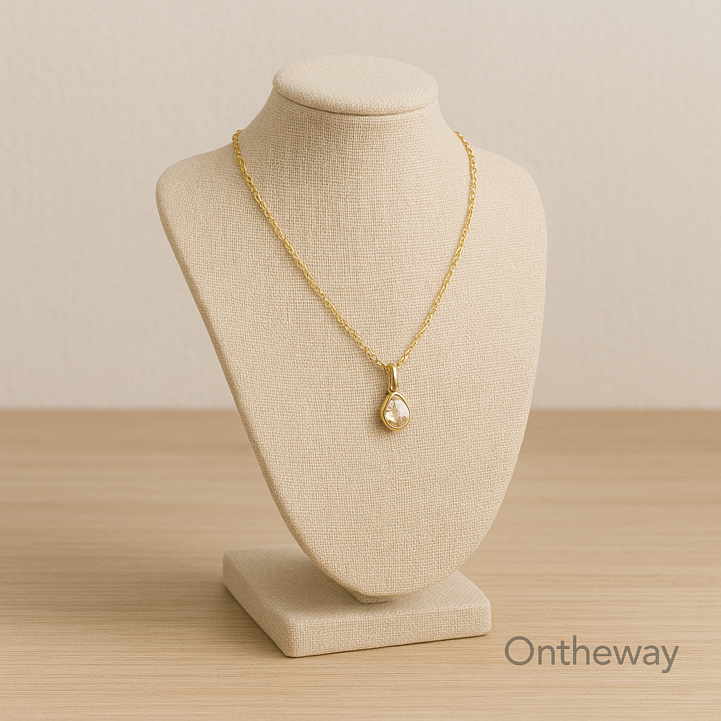 A digital photograph showcases a beige linen jewelry display stand featuring a gold chain necklace with a teardrop gemstone pendant, placed on a wooden surface under warm neutral lighting with a subtle Ontheway watermark, representing elegant minimalist design.